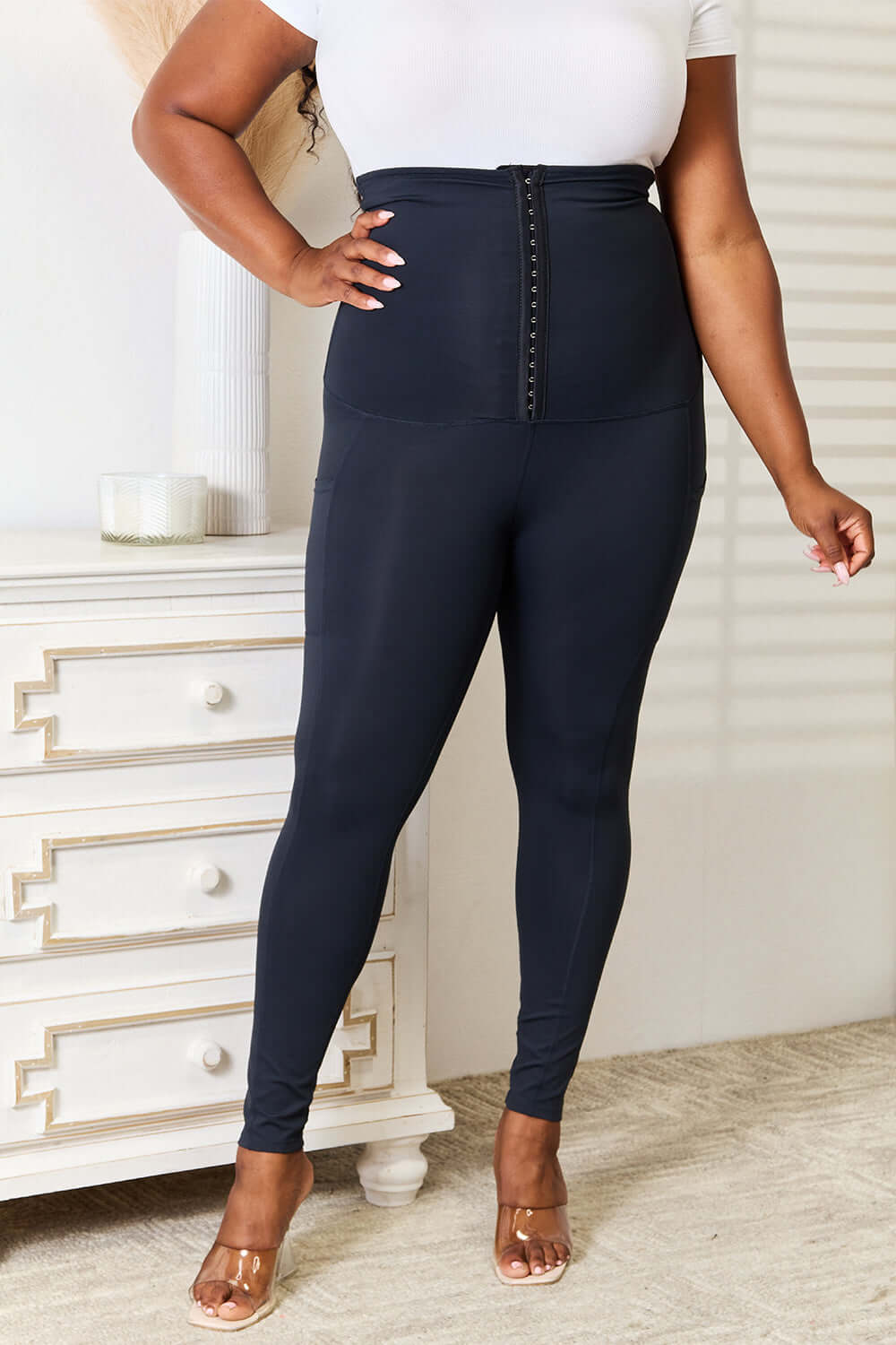 Woman wearing Heimish Full Size Waist Trainer Corset Leggings in black for a sleek, hourglass silhouette and secure fit during workouts.