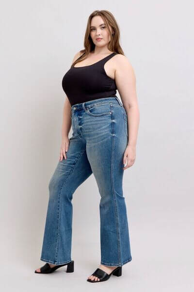 Stylish woman in black tank top and vintage wash jeans showcasing a flattering tummy control design.