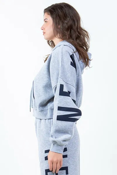 Side view of a woman wearing a grey cropped hoodie with a drawstring, showcasing the trendy graphic design.