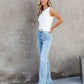 Woman modeling washed straight leg jeans with a white tank top against a neutral backdrop