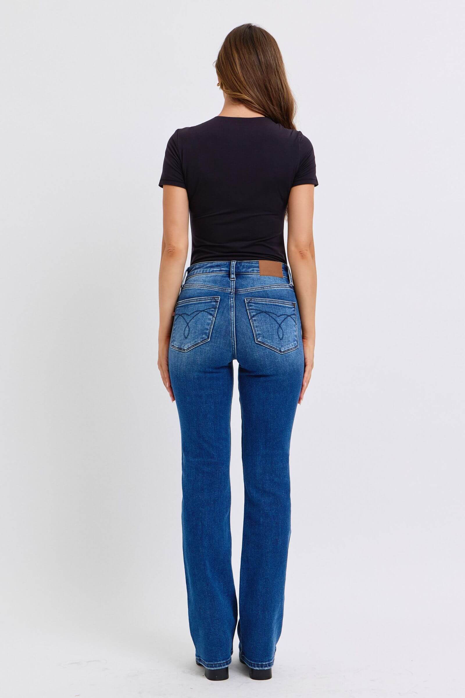 Woman wearing Judy Blue mid-rise bootcut jeans with thermal lining, shot from the back, showcasing a flattering silhouette.