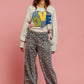 Model wearing BiBi LOVE Heart Patch Slit Sweatshirt with floral pants and cowboy hat, exuding casual style.