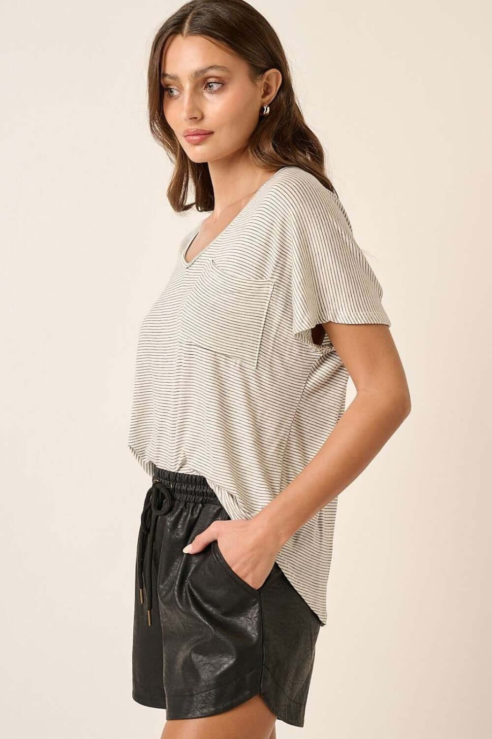 Woman wearing stylish striped v-neck short sleeve t-shirt paired with black shorts.