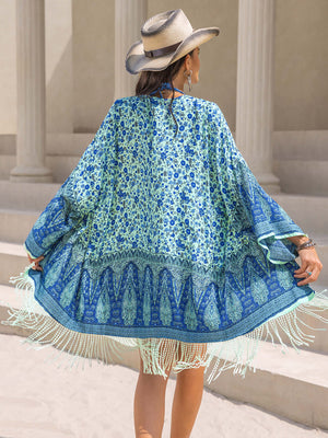 Woman in blue fringe printed cover-up and hat, showcasing playful beachwear style.