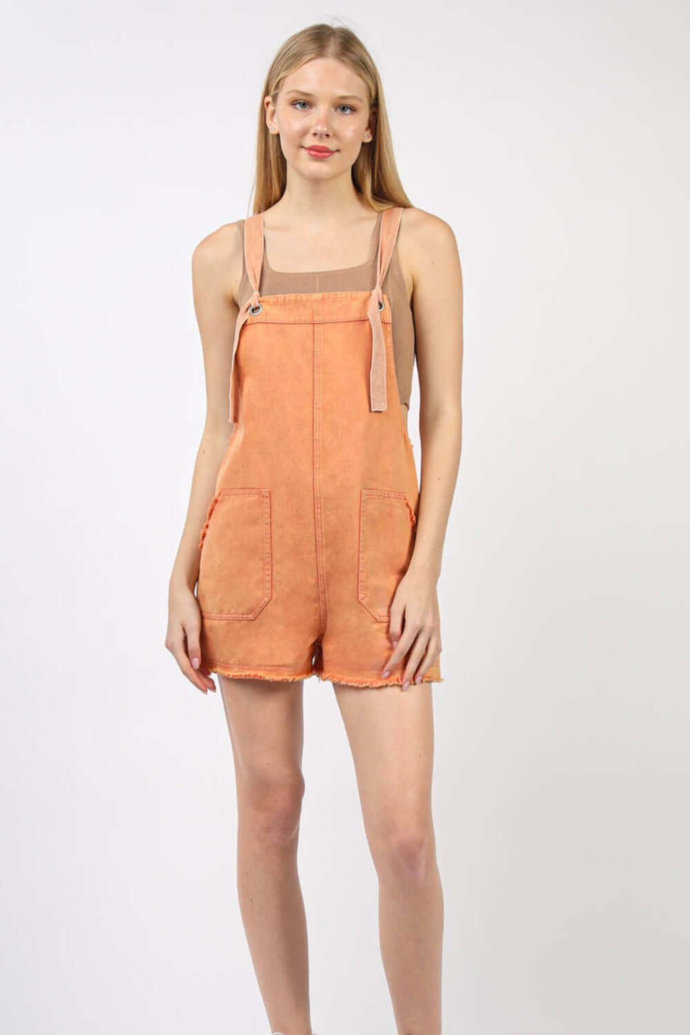 Woman wearing a trendy washed cotton denim casual romper overall with frayed hem, side and back pockets, perfect for vintage fashion lovers.