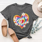 Charcoal graphic round neck short sleeve T-shirt with "Love is Love" rainbow heart print, paired with beige flats and hat.