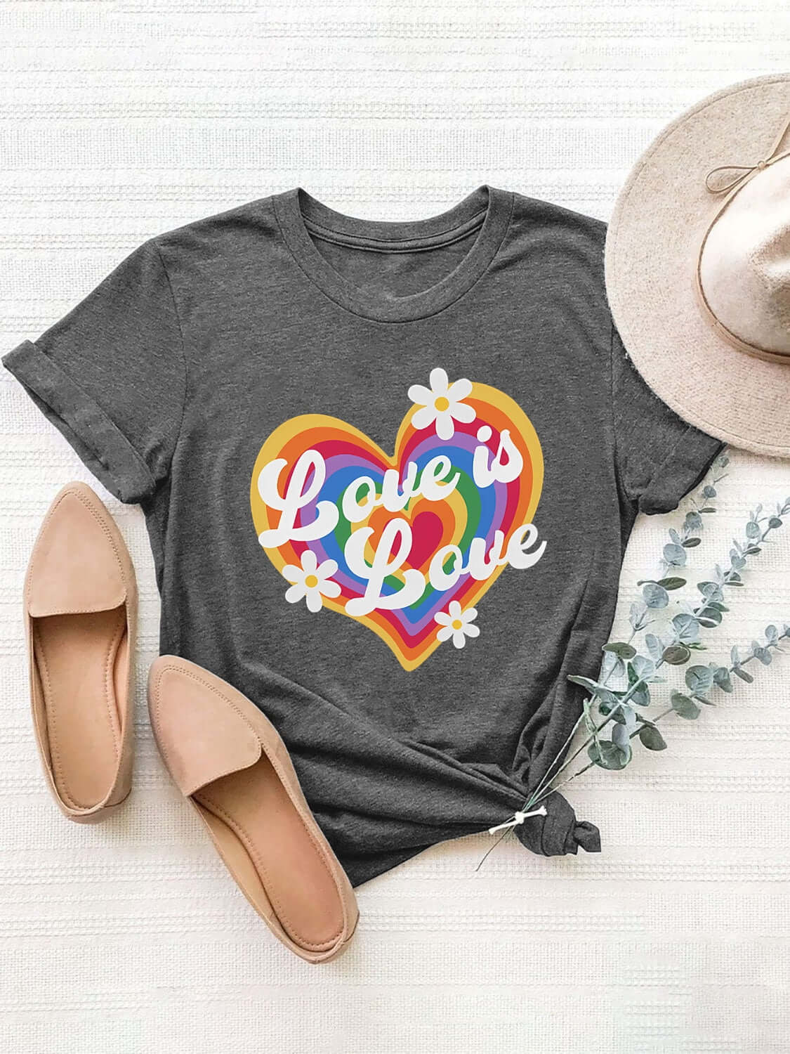 Charcoal graphic round neck short sleeve T-shirt with "Love is Love" rainbow heart print, paired with beige flats and hat.