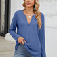 Woman wearing Bella Road Waffle-Knit Notched Long Sleeve T-Shirt in blue with a casual outfit standing on steps.