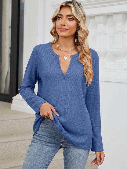 Woman wearing Bella Road Waffle-Knit Notched Long Sleeve T-Shirt in blue with a casual outfit standing on steps.