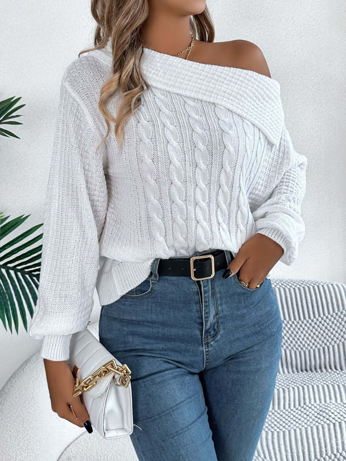 Woman wearing Bella Road Cable-Knit One Shoulder Long Sleeve Sweater in white, paired with jeans and holding a handbag