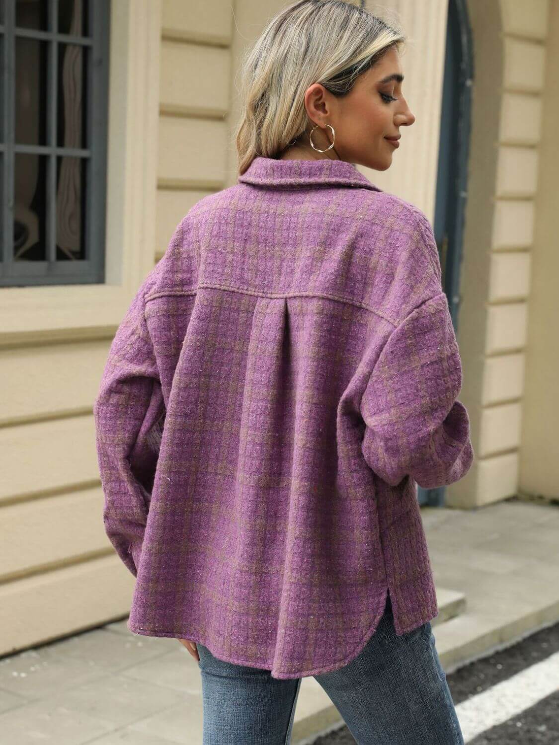 Woman wearing a Bella Road plaid collared neck long sleeve jacket in purple, standing outdoors by a cream-colored building