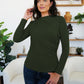 Woman wearing Army Green ruched mock neck long sleeve t-shirt, perfect for fall layering and style, standing in a cozy living room.