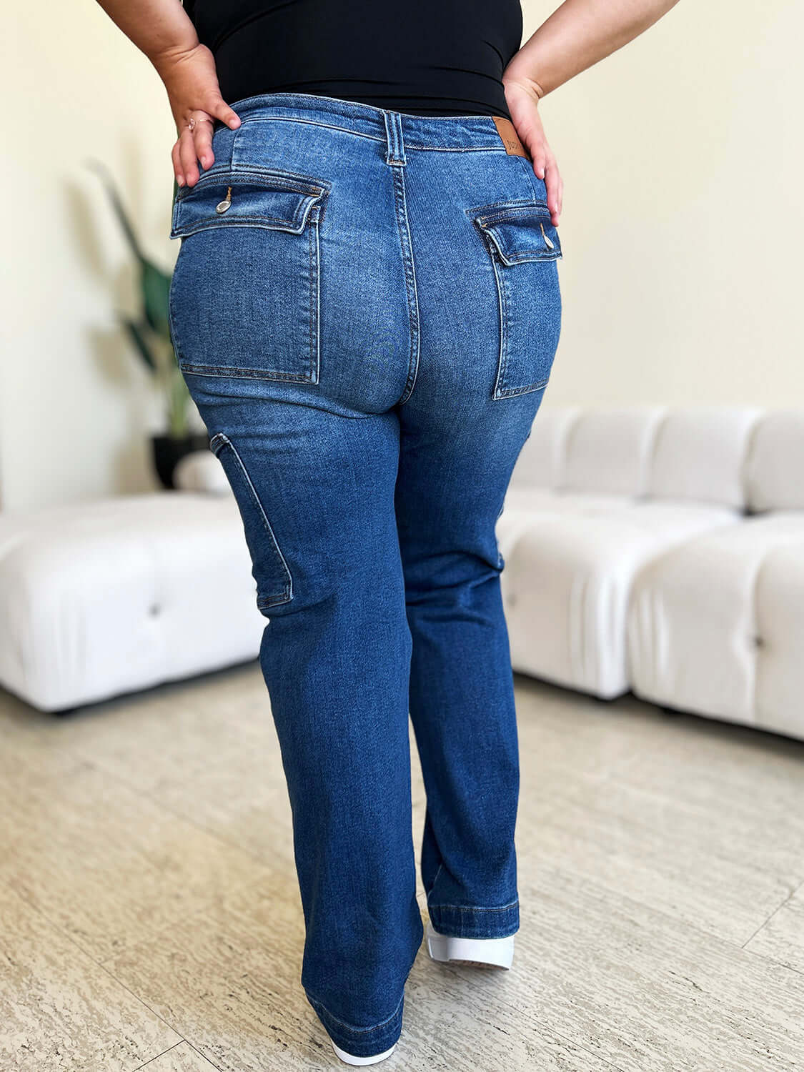 Woman wearing High Waist Straight Cargo Judy Blue Jeans showing back pockets and straight leg fit, standing on wooden floor