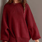 Woman wearing a cozy side slit round neck long sleeve sweater in deep red.