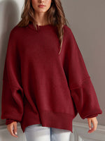 Woman wearing a cozy side slit round neck long sleeve sweater in deep red.