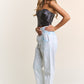 Woman wearing J.NNA sequin strapless bustier top with light denim pants, showcasing a chic and glamorous party outfit.