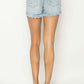 Woman wearing Risen Jeans Raw Hem Denim Shorts, showcasing the stylish frayed edges and back pocket details.