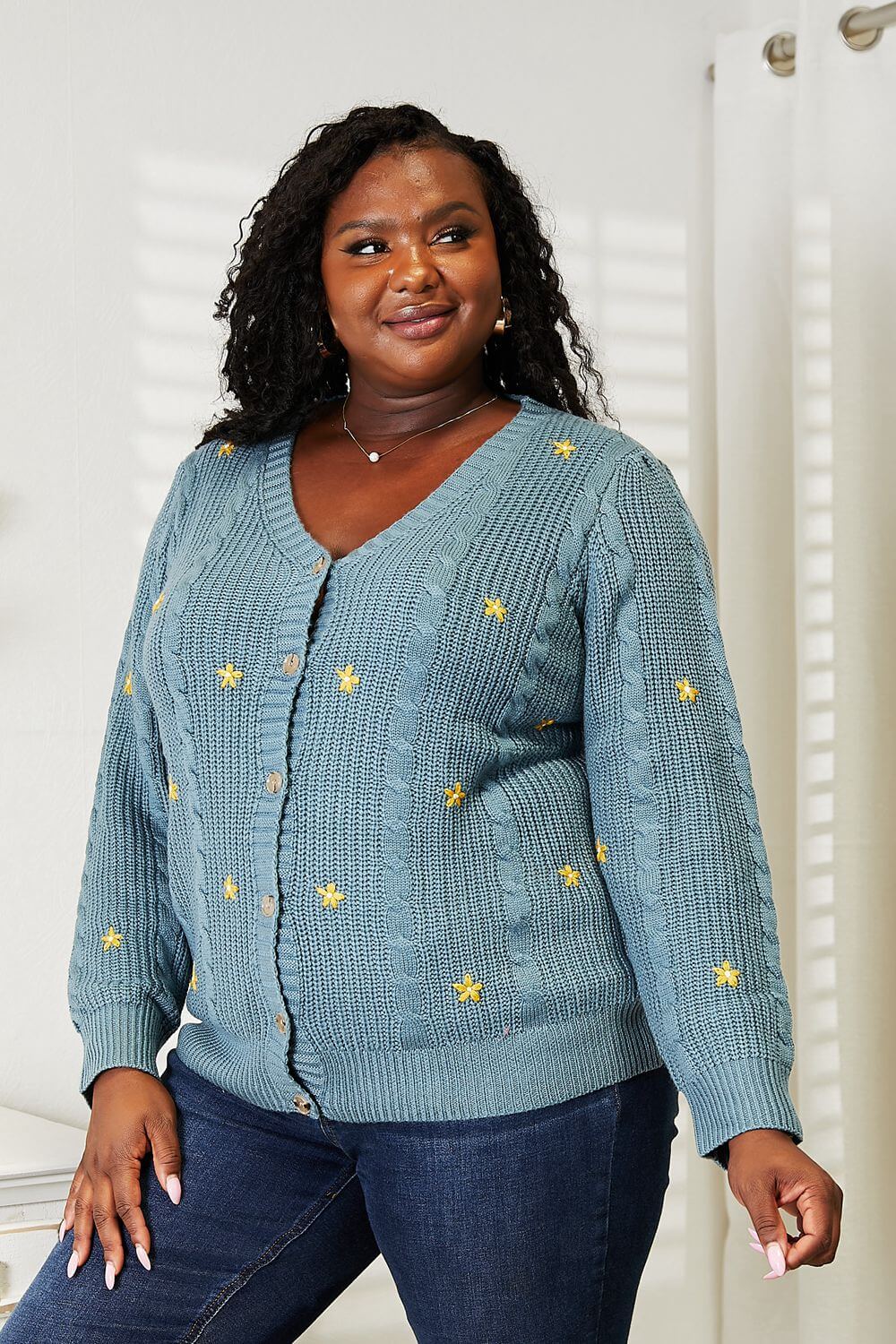 Woman wearing HEYSON floral embroidered cable cardigan, showcasing cozy and elegant knit fashion with nature-inspired embroidery.