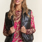 Woman in J.NNA metallic puffer vest, styled with a floral top and sequin skirt, showcasing trendy and warm fashion.