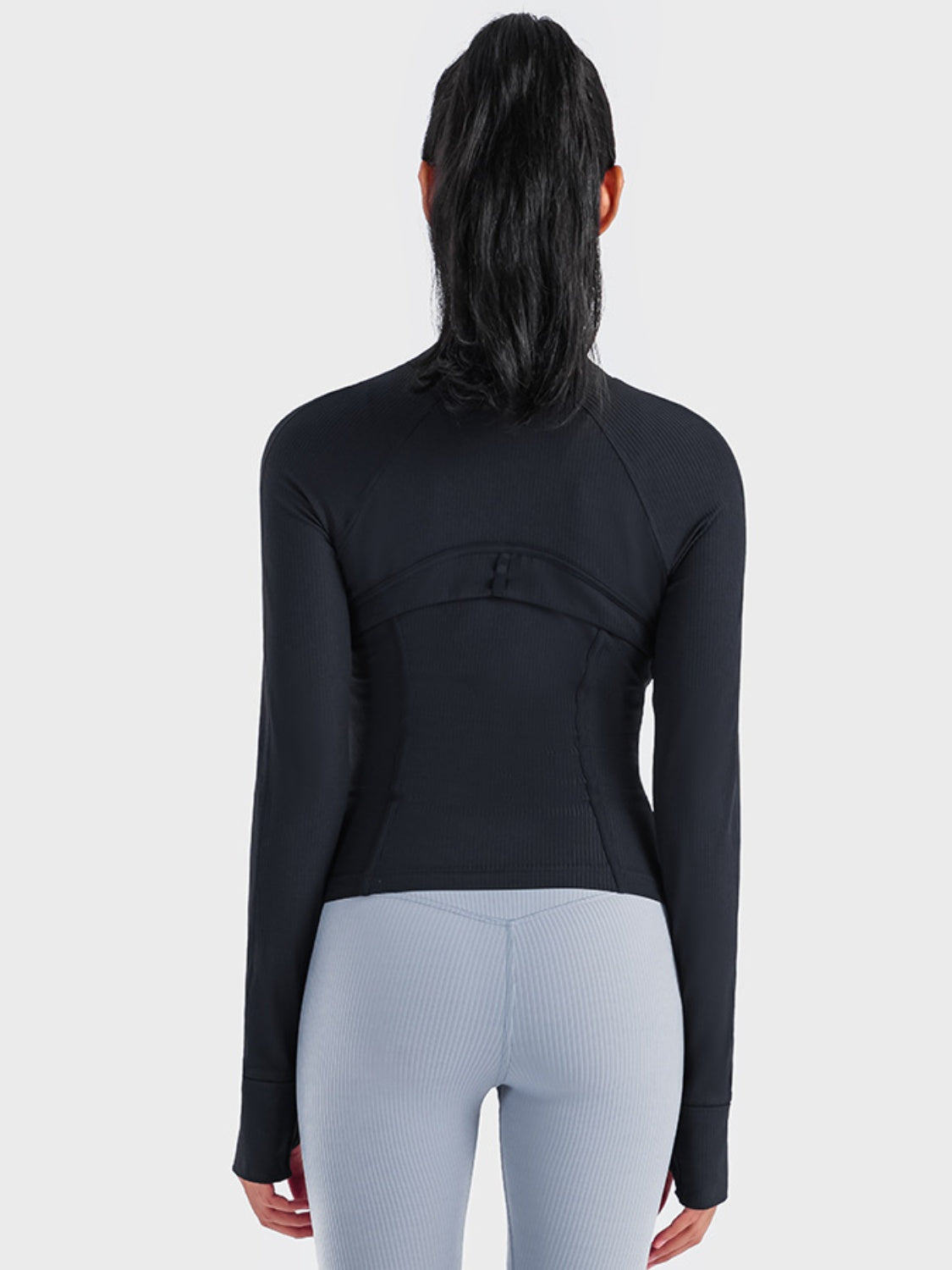 Back view of a woman wearing the sleek Millennia Zip-Up Long Sleeve Sports Jacket in black, perfect for workouts and activewear.