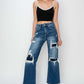 Model wearing Risen Jeans high rise patch detailed wide leg crop jeans with a black crop top and high heels.