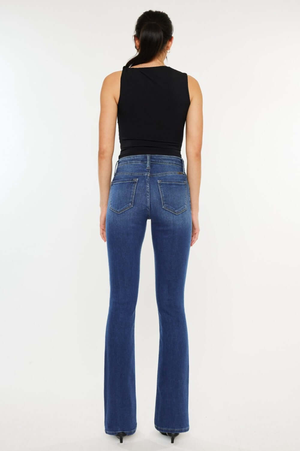 Woman wearing Kancan high-rise slim bootcut jeans in medium stone wash showcasing classic 5-pocket design and flattering fit.