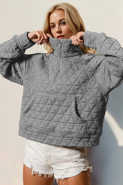 Woman wearing gray quilted half zip long sleeve sweatshirt with pocket and white shorts. Cozy and stylish fashion look.