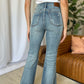 Woman wearing Judy Blue medium rise tummy control destroy flare jeans, showcasing back view, with distressed details and flattering fit.