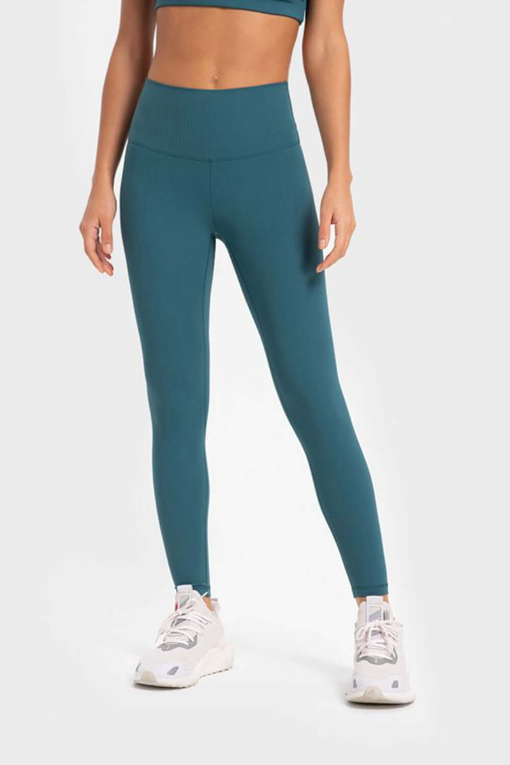 Woman in teal Millennia yoga leggings with wide waistband, showcasing comfort and flexibility for workouts.