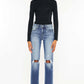 Stylish model in high waist distressed hem detail cropped straight jeans with a black top and white sneakers.