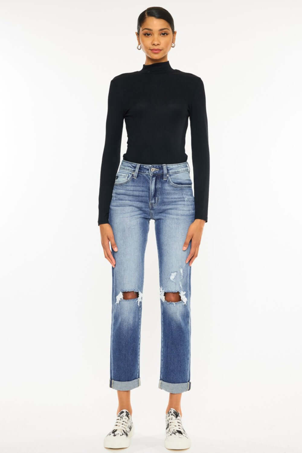 Stylish model in high waist distressed hem detail cropped straight jeans with a black top and white sneakers.