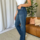 Woman wearing RFM Full Size High Rise Straight Tummy Control Jeans in a living room setting