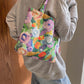 Woman holding a medium-sized printed canvas handbag with zipper, featuring colorful floral design.