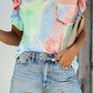 Woman wearing Bella Road Ruffled Printed Cap Sleeve T-Shirt in colorful tie-dye, paired with distressed denim shorts.