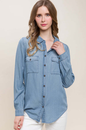 Woman wearing a scooped hem button-up denim shirt.