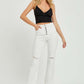 Woman wearing high rise button fly straight ankle jeans by Risen Jeans, styled with a black crop top and sandals.