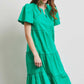 Woman wearing a green HEYSON midi dress with ruffled tiers, made from cotton poplin fabric, perfect for warm weather days.