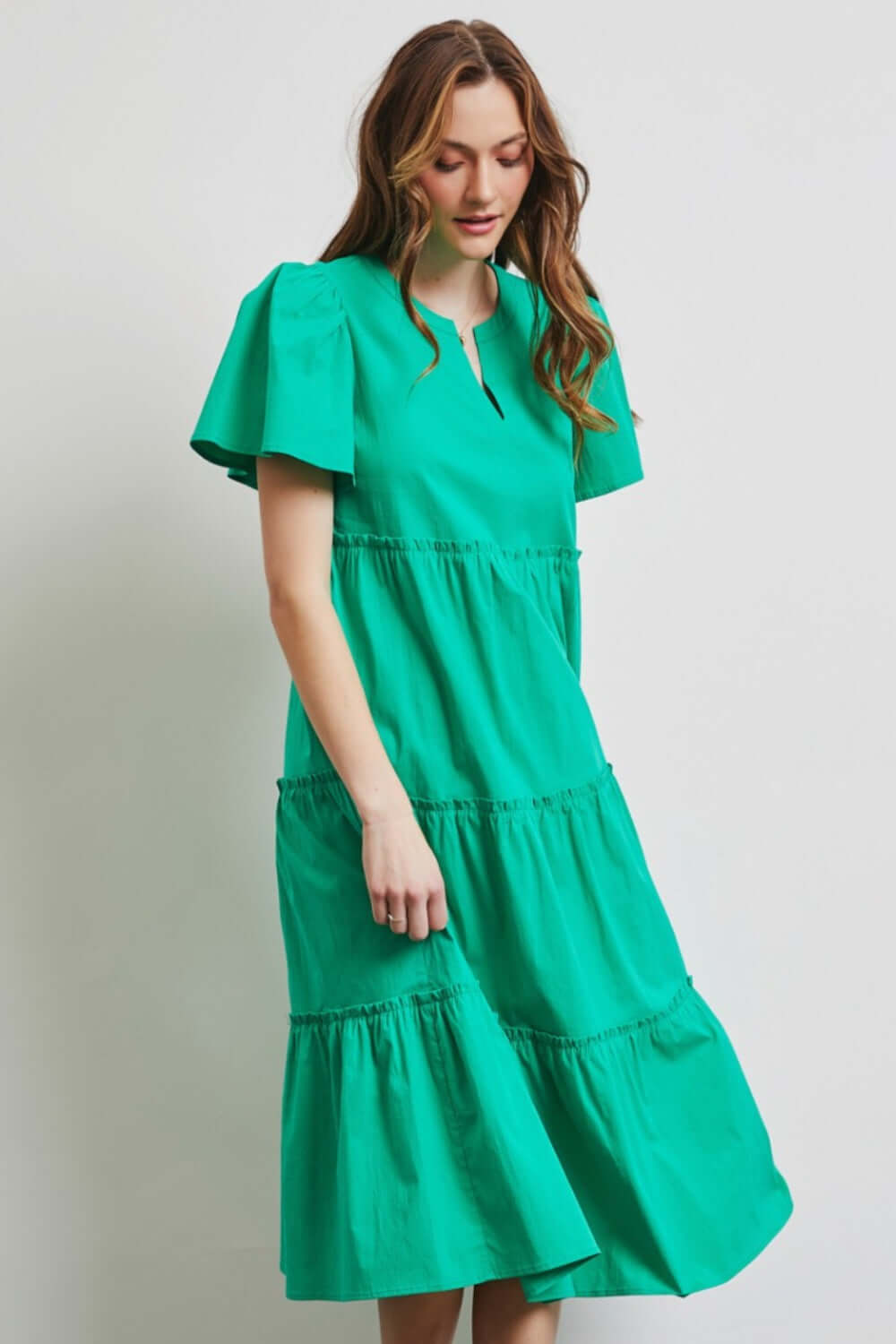 Woman wearing a green HEYSON midi dress with ruffled tiers, made from cotton poplin fabric, perfect for warm weather days.