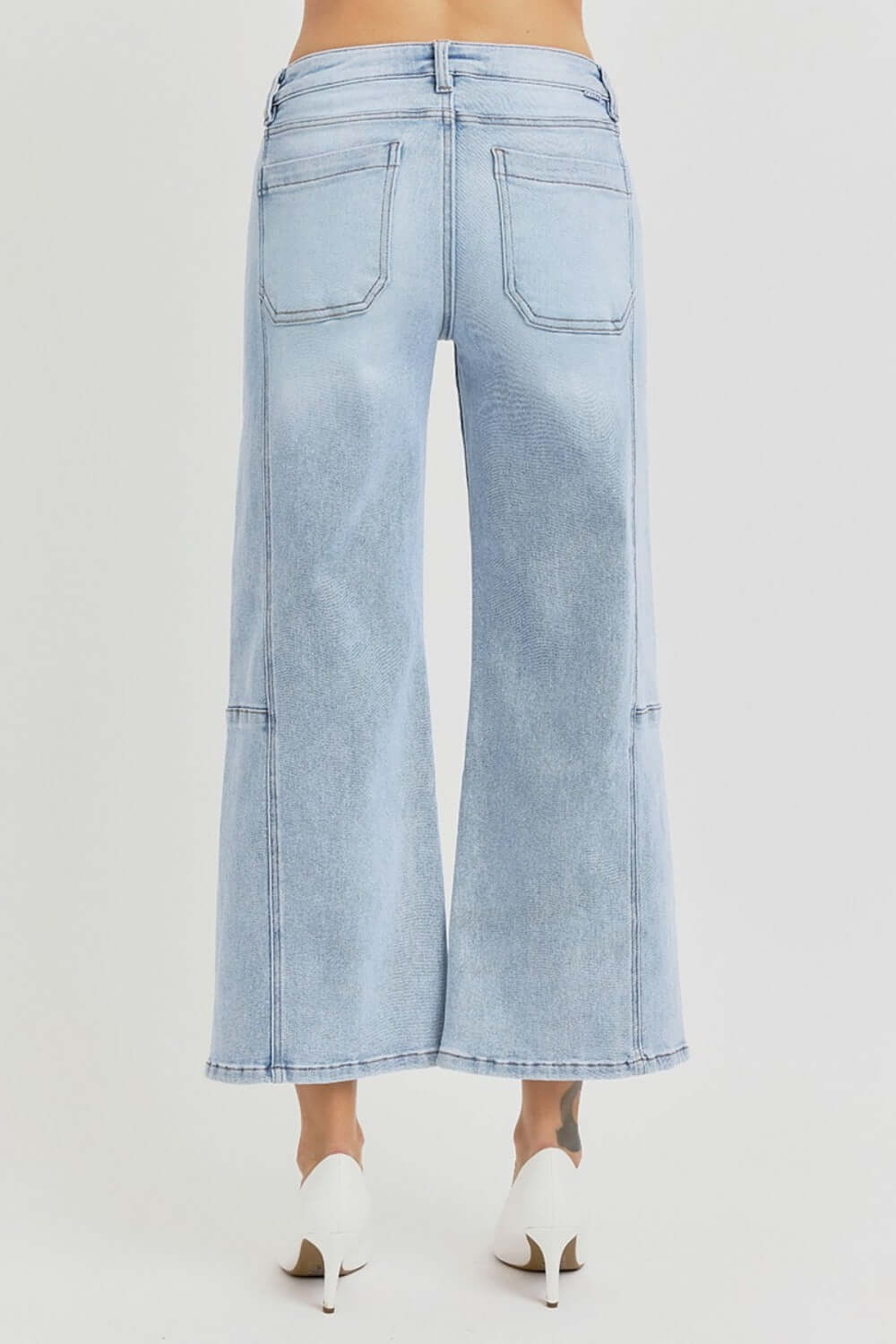 RISEN high rise wide leg crop jeans with seamed detail shown from the back, paired with white heels for a chic look.