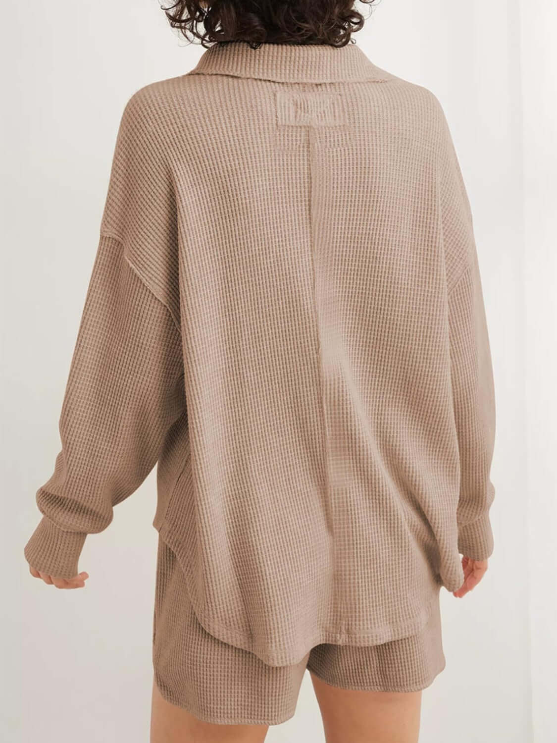 Woman wearing a beige waffle-knit long sleeve sweatshirt with a johnny collar, viewed from the back.