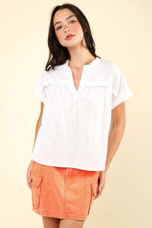 Woman wearing a notched short sleeve washed knit top paired with an orange denim skirt.