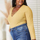 Woman wearing All About Details full size ribbed bodysuit with lace-up caged neck detail and high-waisted jeans, showcasing a chic, flattering fit