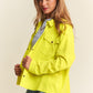 Woman in a bright yellow J.NNA snap down long sleeve high low shacket with a relaxed fit and trendy silhouette.