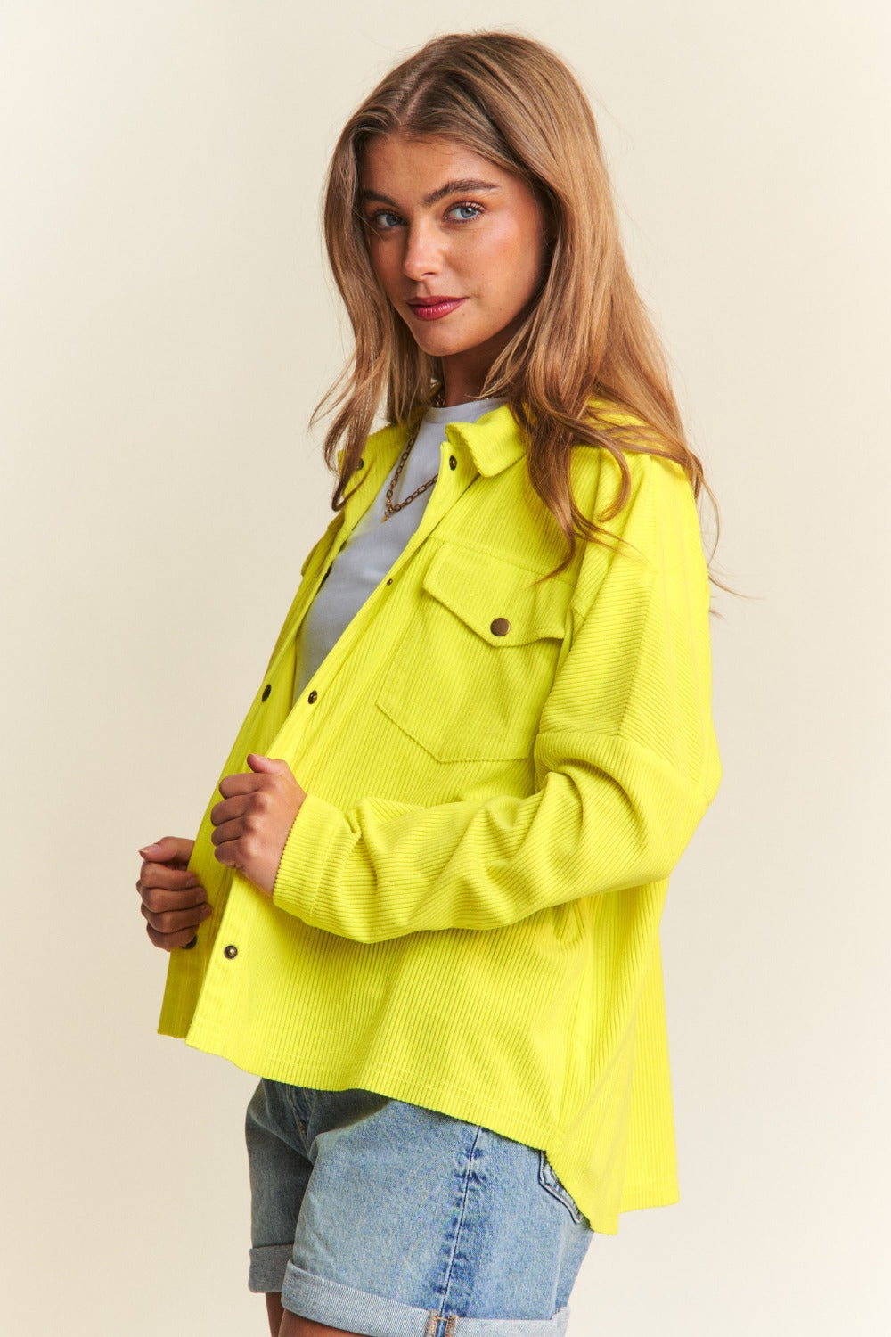 Woman in a bright yellow J.NNA snap down long sleeve high low shacket with a relaxed fit and trendy silhouette.