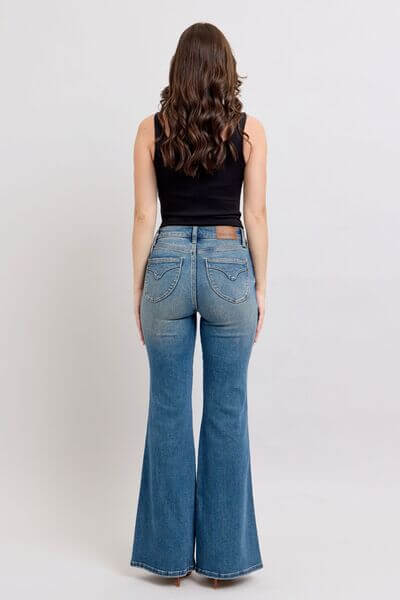 Model wearing Judy Blue mid rise tummy control vintage wash jeans from the back, showcasing retro style and flattering fit.