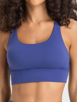 Model wearing a stylish Millennia crisscross scoop neck active tank in vibrant blue, perfect for workouts and active lifestyles.