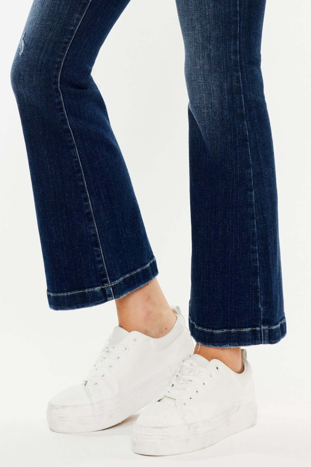 Stylish Kancan mid-rise button fly flare jeans in medium wash paired with white sneakers.