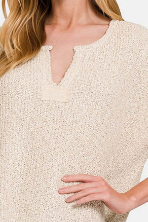 Beige short sleeve side slit sweater with textured knit fabric, modeled by a woman showing the neckline and part of the sleeve.