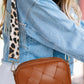 Stylish woman wearing a brown Cassette Woven Crossbody Bag with a trendy leopard print strap.