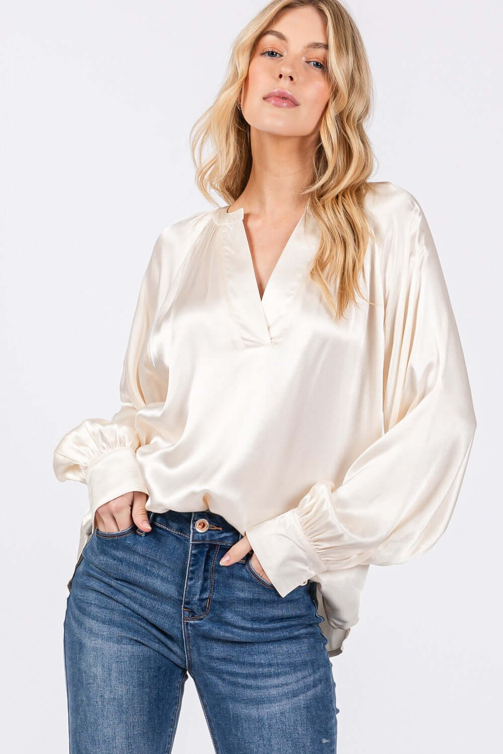 Woman wearing a notched long sleeve blouse with raglan sleeves and split neckline, paired with blue jeans, showcasing a versatile and elegant look.